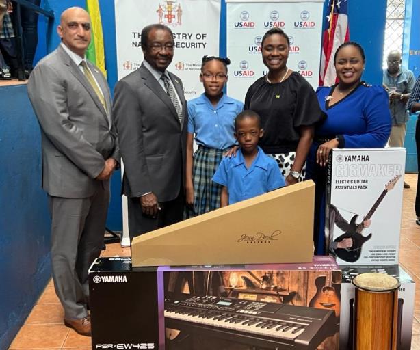 Minister of State in the Ministry of National Security, the Hon. Juliet Cuthbert-Flynn (second right) and US Ambassador to Jamaica, His Excellency Nickolas Perry (second left) hands over several musical instruments to the Principal of Flankers Primary and Junior High, Collette Barnes yesterday (January 25). USAID Jamaica Country Representative, Dr. Jadiev Singh and two students, Ravena Palmer and Jaden Ennevor also share the moment.