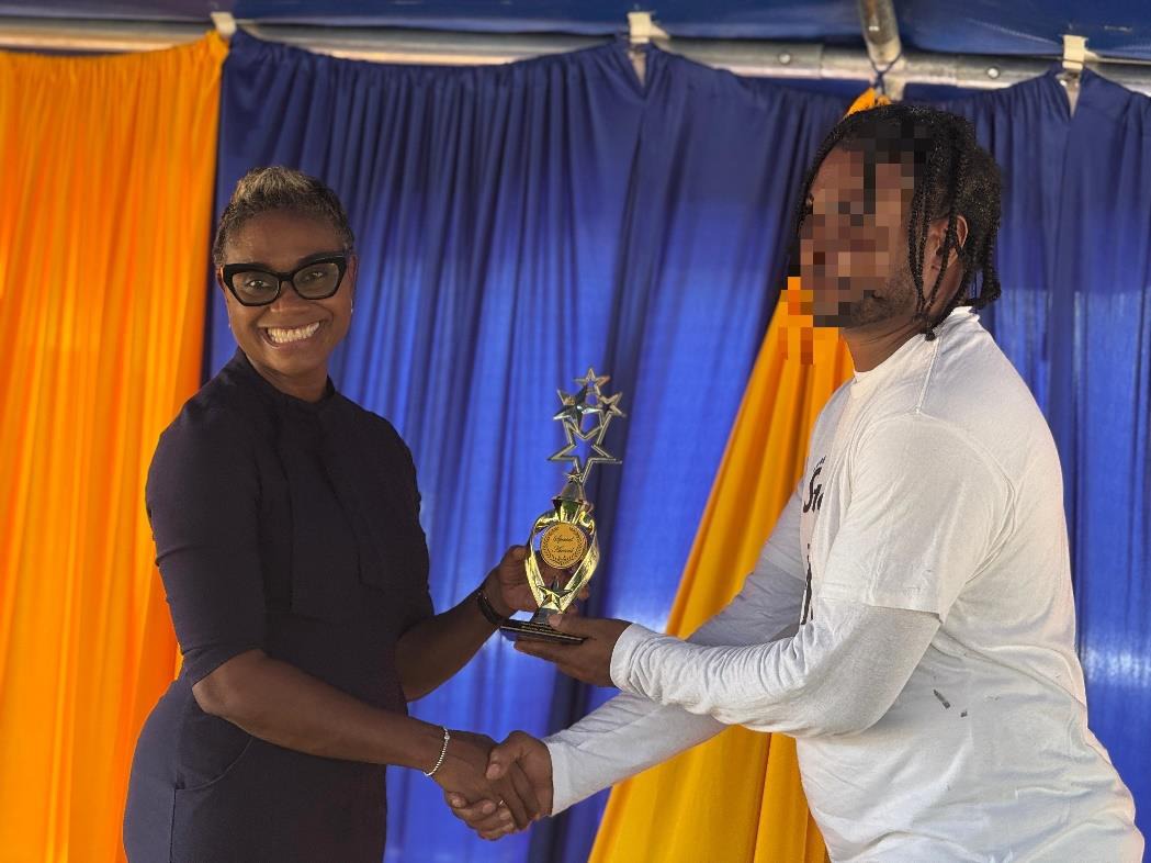 Minister of State in the Ministry of National Security, the Hon. Juliet Cuthbert-Flynn proudly presents one of the inmates at the Tamarind Farm Adult Correctional Centre with the ‘Most Outstanding Student’ award at the correctional centre’s Agriculture and Awards Day on Tuesday (June 24).