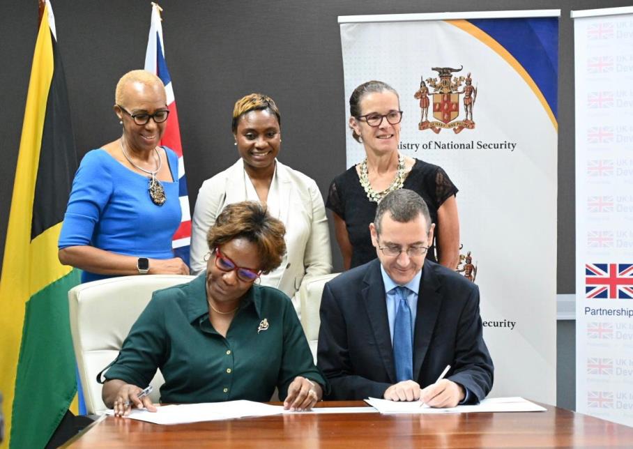 Permanent Secretary in the Ministry of National Security, Ambassador Alison Stone Roofe (front-left) and Head of the Political and Development Team at the British High Commission, Oliver Blake sign a Memorandum of Understanding for a J$2.9B UK-Jamaica Violence Prevention Partnership (VPP) Programme. The signing ceremony was held earlier today (April 24) at the Ministry of National Security in Kingston. Looking on are Minister of Education and Youth, Hon. Fayval Williams (back-left), Minister of State in the