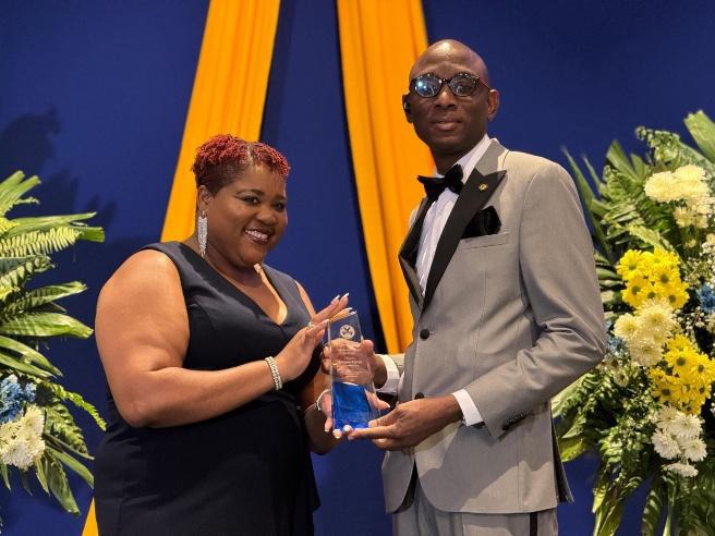 Chief Technical Director in the Ministry of National Security and Peace, Ms. Shauna Trowers (left), presents Head Chaplin in the Department of Correctional Services, Rehabilitation and Probation Aftercare Services Branch, Reverend Ricardo Taylor, with the Divisional Employee of the Year Award in the area of Spiritual Leadership, Compassion and Commitment to Emotional Wellbeing of Staff and Offender Clients. The presentation was made at the Department of Correctional Services Annual Staff Awards Ceremony on 