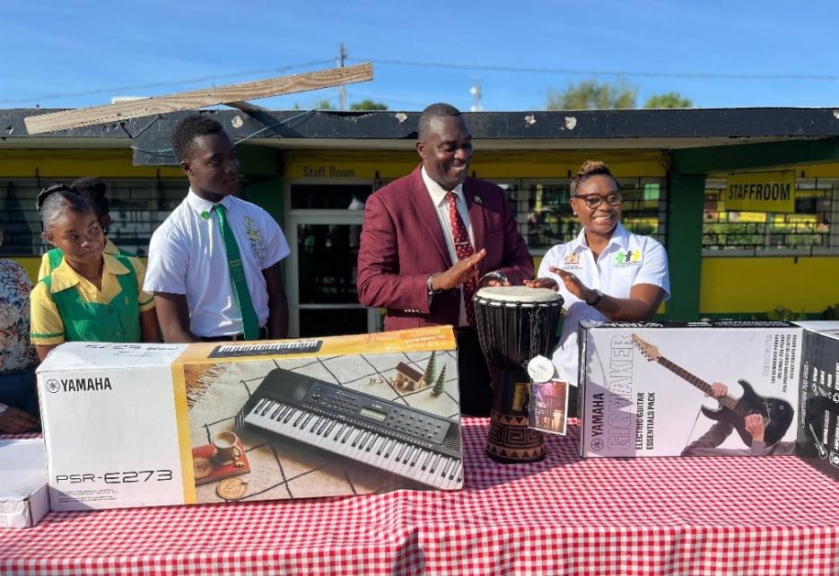 Minister of State in the Ministry of National Security, the Hon. Juliet Cuthbert-Flynn (right) shares a light moment with Principal of the Old Harbour High School, Lynton Weir (second right) during the handing-over ceremony of musical instruments to the school yesterday (May 27). Head Boy, Acado Brown and choir member Gianna Francis look on.